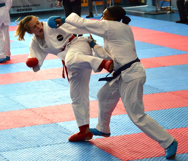 Dwie zawodniczki karate walczą ze sobą, wymieniają ciosy.